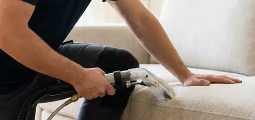 Professional upholstery cleaner deep-cleaning a fabric sofa with a handheld extraction tool, Stockton, CA.